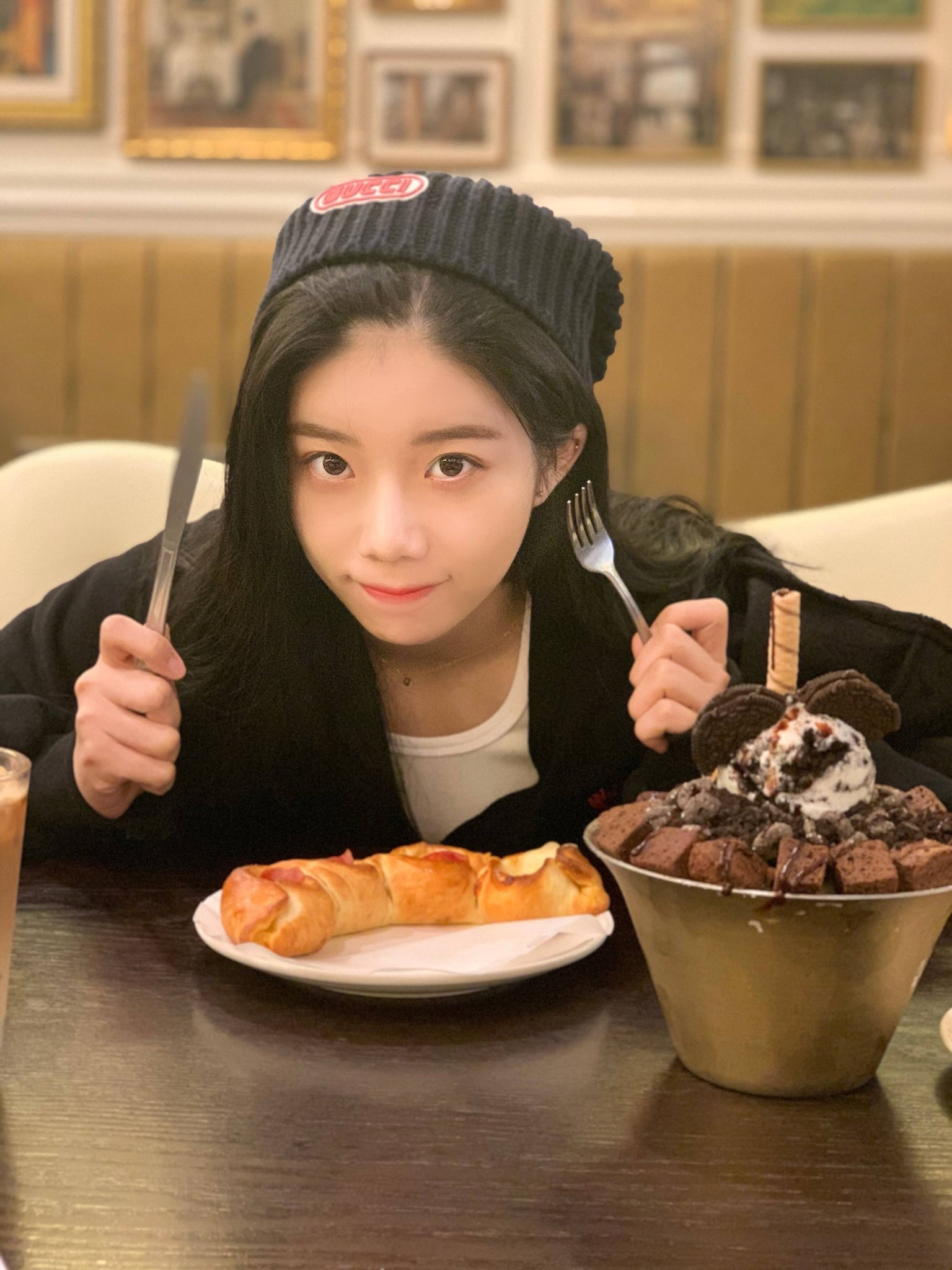 smy sitting at a table smiling cutely while holding a knife and a fork up