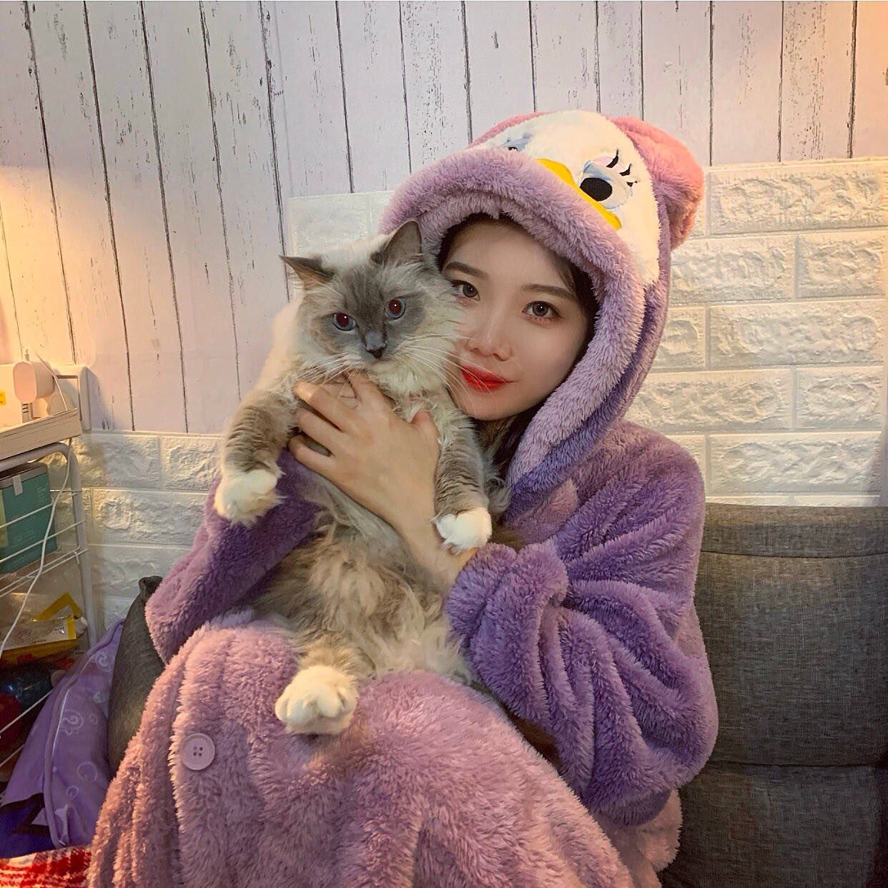 smy wearing a fluffy donald duck onesie and holding her cat